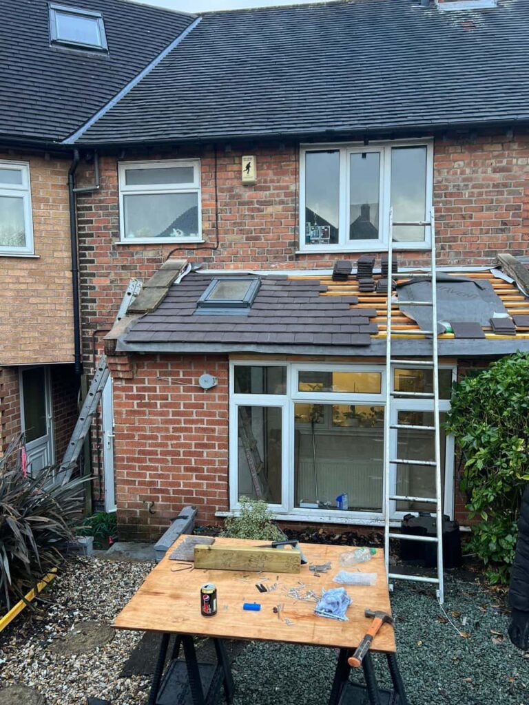 This is a photo of a roof extension that is having new roof tiles installed. This is a photo taken from the roof ridge looking down a tiled pitched roof on to a flat roof. Works carried out by Caterham Roofing Repairs