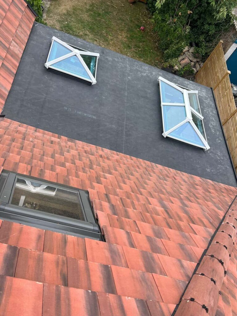 This is a photo taken from the roof ridge looking down a tiled pitched roof on to a flat roof. Works carried out by Caterham Roofing Repairs